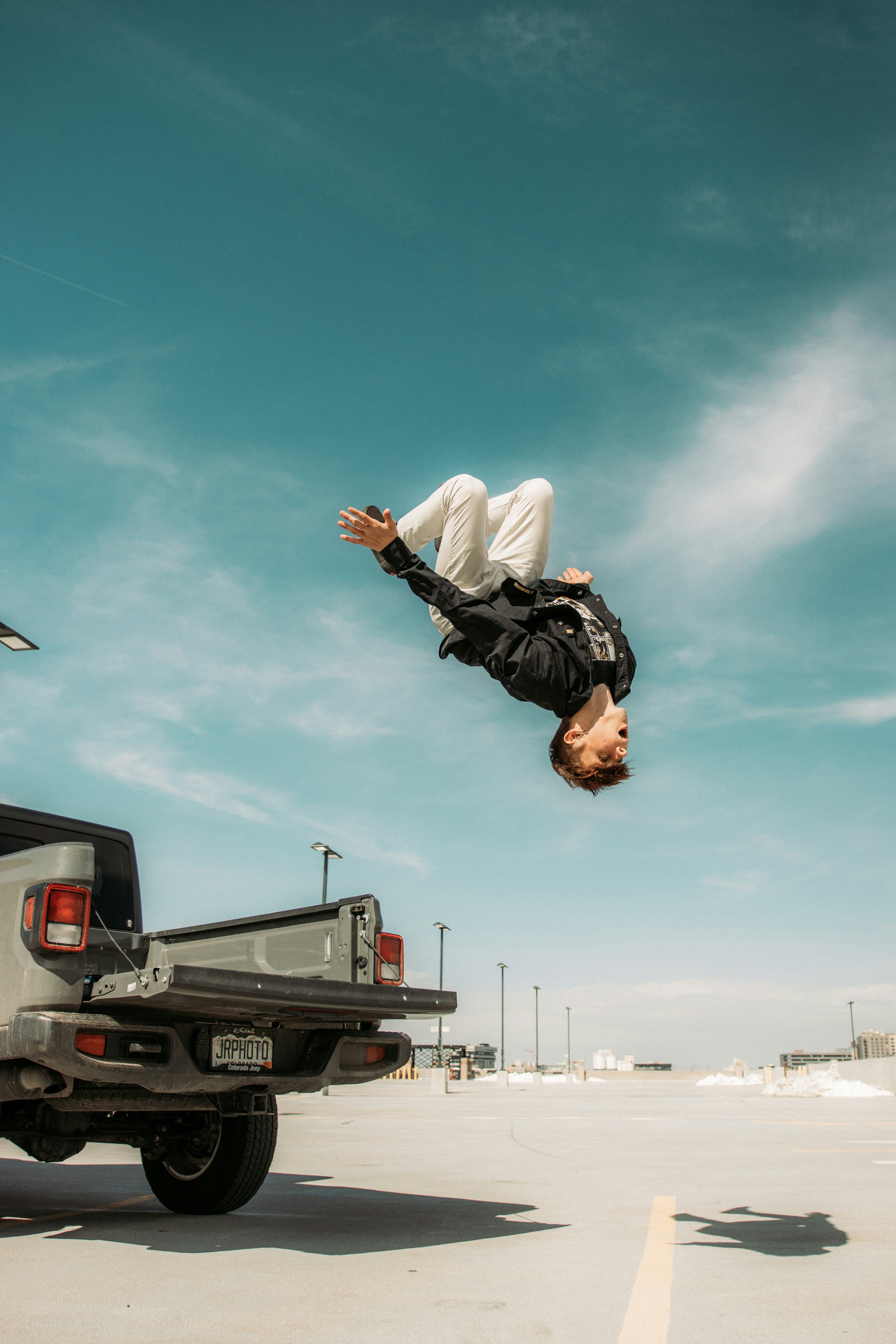 man in black jacket and white pants jumping on air during daytime